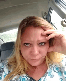 a woman sitting in a car with her hand on her head