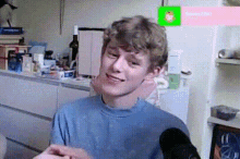 a young man is sitting in front of a refrigerator in a kitchen and smiling .