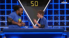 a man and a boy are playing a game show with the number 50 on the screen behind them