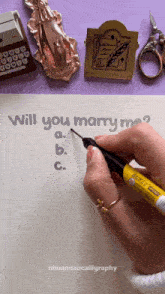 a person is writing the question will you marry me