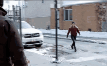 a woman crosses the street in front of a white dodge