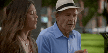 an elderly man wearing a hat sits next to a woman