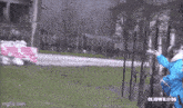 a person in a blue jacket is standing in front of a fence and a sign that says cliowillie96