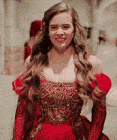 a woman wearing a red dress and gloves smiles for the camera