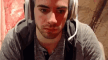 a young man wearing headphones and a microphone is sitting in front of a computer screen .
