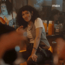 a woman with curly hair is sitting at a table with a max logo in the corner .