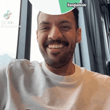 a man with a beard and mustache is smiling with a bangladeshi filter on his head