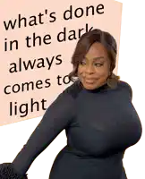a woman stands in front of a poster that says what 's done in the dark always comes to light