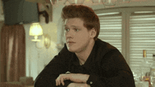 a man in a black shirt sits at a bar looking at something