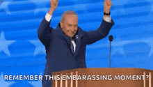 a man in a suit and tie is standing behind a podium with his arms in the air .