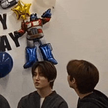 a group of young men are standing in front of a robot balloon .