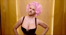 a man wearing a pink wig and a black bra is standing next to a woman with large breasts .