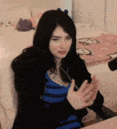 a woman in a blue striped shirt is clapping her hands in front of a bed