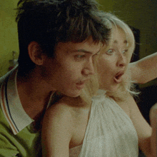 a man in a green sweater holds a woman in a white dress in his arms