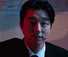 a man in a suit and tie is looking at the camera with a bloody face .