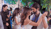 a man and a woman are dancing together in a crowd of people at a wedding reception .