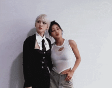 a couple of women standing next to each other with one wearing a white tank top