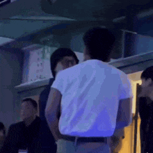 a man in a white shirt is standing next to another man in a dark room .