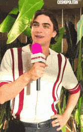 a man is holding a pink cosmopolitan microphone and smiling