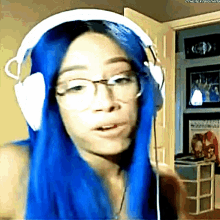 a woman with blue hair is wearing headphones