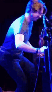 a man in a blue shirt is standing in front of a purple light