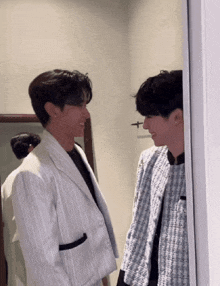 two men are standing next to each other in a room and looking at each other