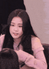 a woman with long black hair is sitting in a chair and looking at the camera .