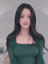 the woman is wearing a green sweater and a necklace .