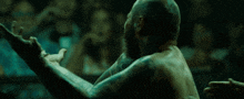 a man with a beard and tattoos on his back stands in front of a crowd of people