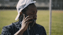 a man wearing a hat that says ' king mighty ' on it is talking on his cell phone