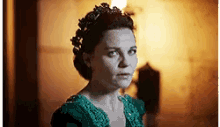 a woman in a green dress with a tiara on her head .