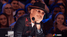 a man sitting in front of a microphone with an a on his hat
