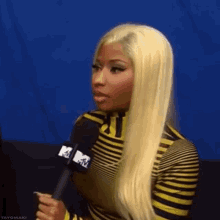 a woman with blonde hair is holding a microphone in her hand .