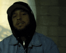 a man wearing a hooded jacket and a hat with the letter t on it
