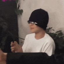 a person wearing a white shirt and a black hat with the letter r on it