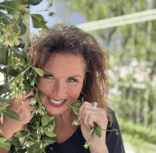 a woman with a ring on her finger is smiling and holding a flower in her mouth