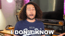 a man with curly hair wearing a blue shirt that says i don 't know
