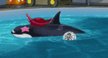 a toy whale with a red seat and a star on it is in the water