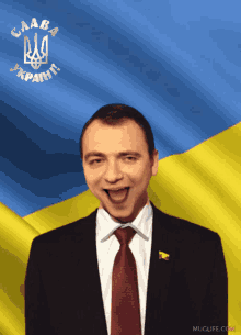 a man in a suit and tie stands in front of a flag that says " слава украiнi "