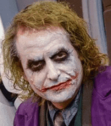 a close up of the joker 's face with a purple jacket on