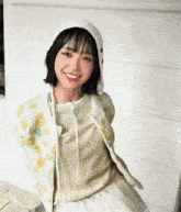 a young woman wearing a white hat and a floral jacket is smiling .