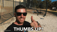 a man wearing sunglasses giving a thumbs up