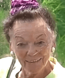 a woman with a purple flower in her hair is smiling .