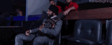 a man in a suit is holding a wrestling championship while two other men look on