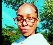 a close up of a woman wearing glasses and a white shirt .