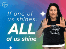 a woman stands in front of a banner that says if one of us shines all of us shine