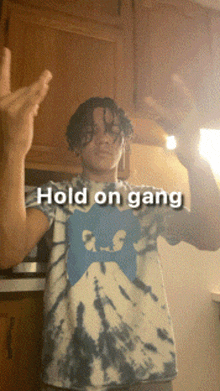 a man wearing a tie dye shirt with the words hold on gang written on it