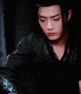 a man with long black hair has a red flower on his head