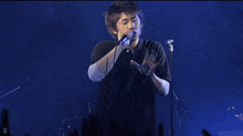 a man singing into a microphone with the letter d visible in the background