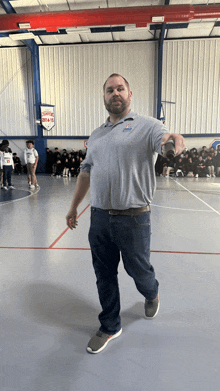 a man stands in front of a basketball court with a sign on the wall that says justice league